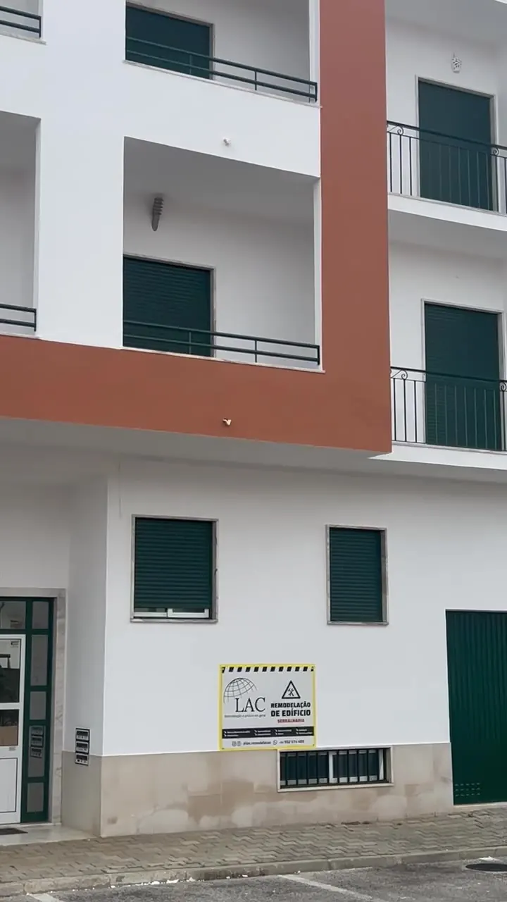 Fachada de edifício concluída, com placa de obra LAC visível